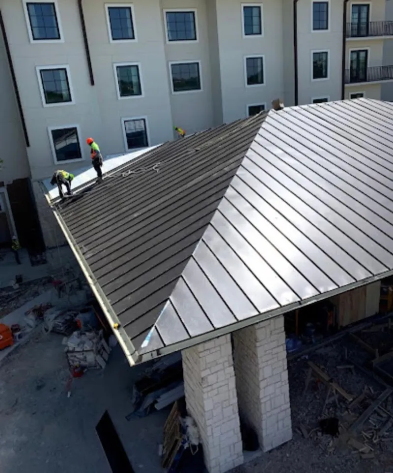Crew installing standing seam metal roof panels on a commercial project in Walled Lake
